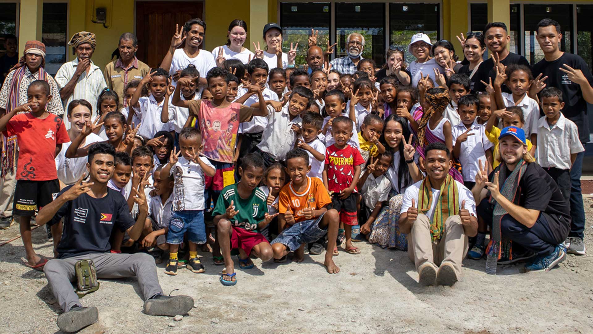 A large group of people before a school building in Timor