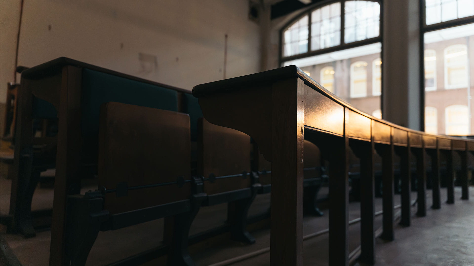 Historic lecture hall with wooden seating at TU Delft campus monument.