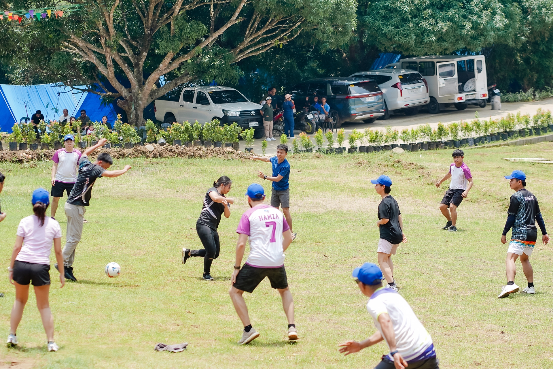 A lively outdoor footbal game is taking place on a sunny grassy field.
