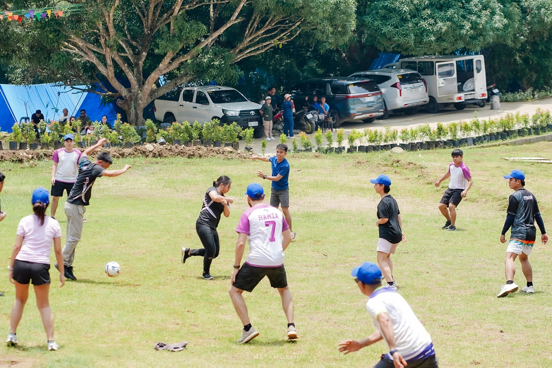 A lively outdoor footbal game is taking place on a sunny grassy field.