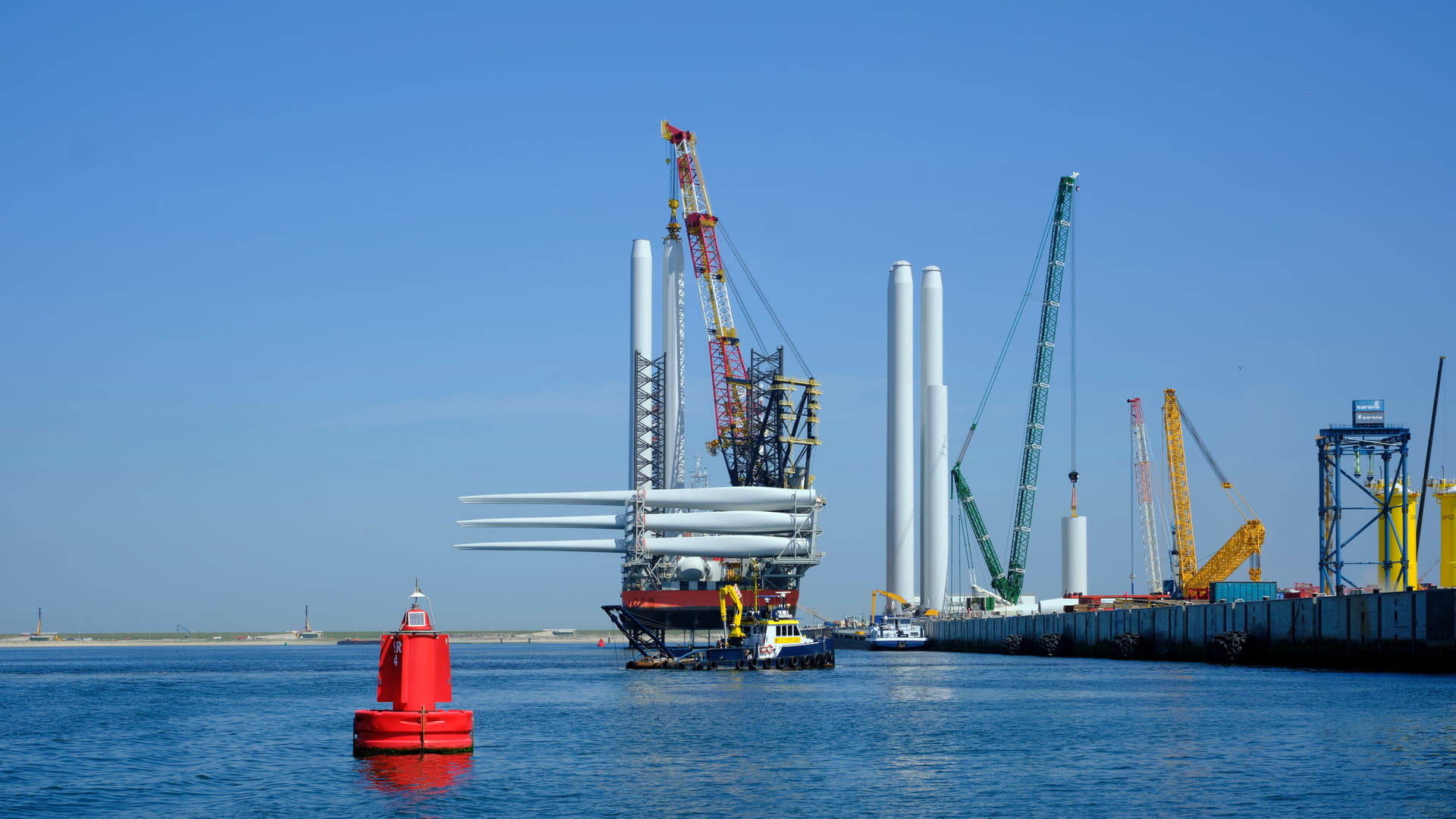 A large offshore vessel with a crane and a helipad is moored in the seaport of Rotterdam. A Jack-up vessel for use in the offshore wind industry