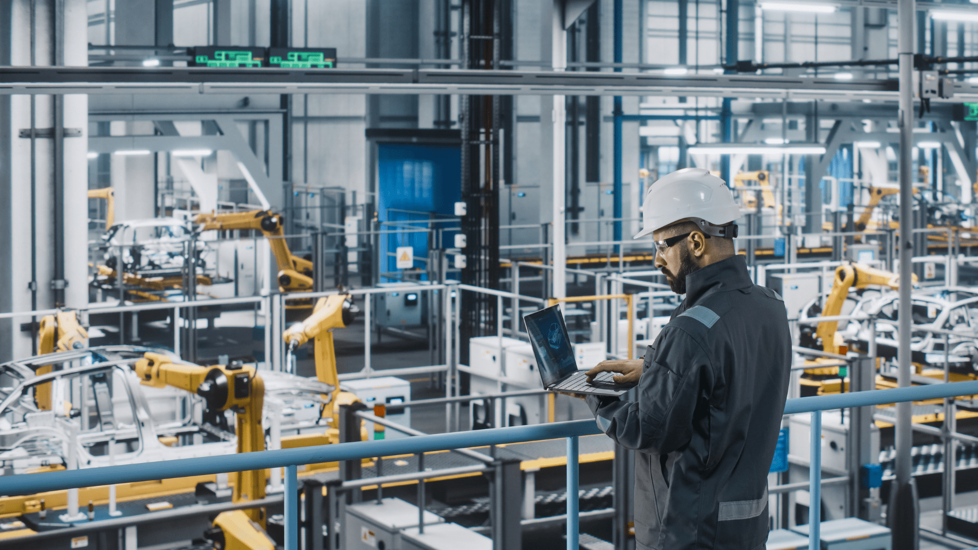 A plant manager oversees a manufacturing plant while using simulation software to help optimise production