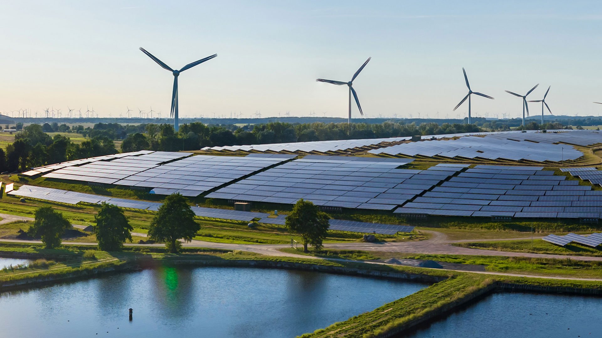 Field of solar panels and three wind turbines in the background