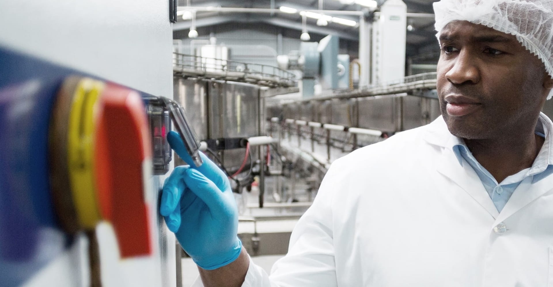 Industrial technician operating machinery in a modern factory setting.