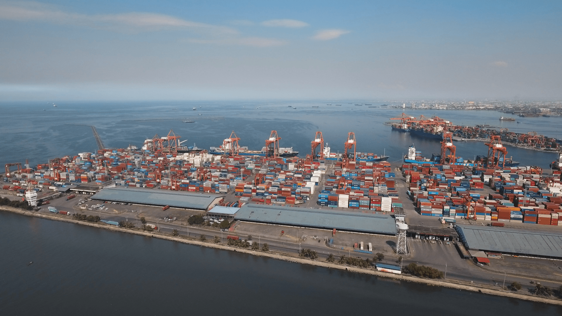 Aerial view industrial cargo port with ships and cranes. View of the cargo port and container terminal. Container cranes in Manila Bay. Cargo ship in industrial port. Manila