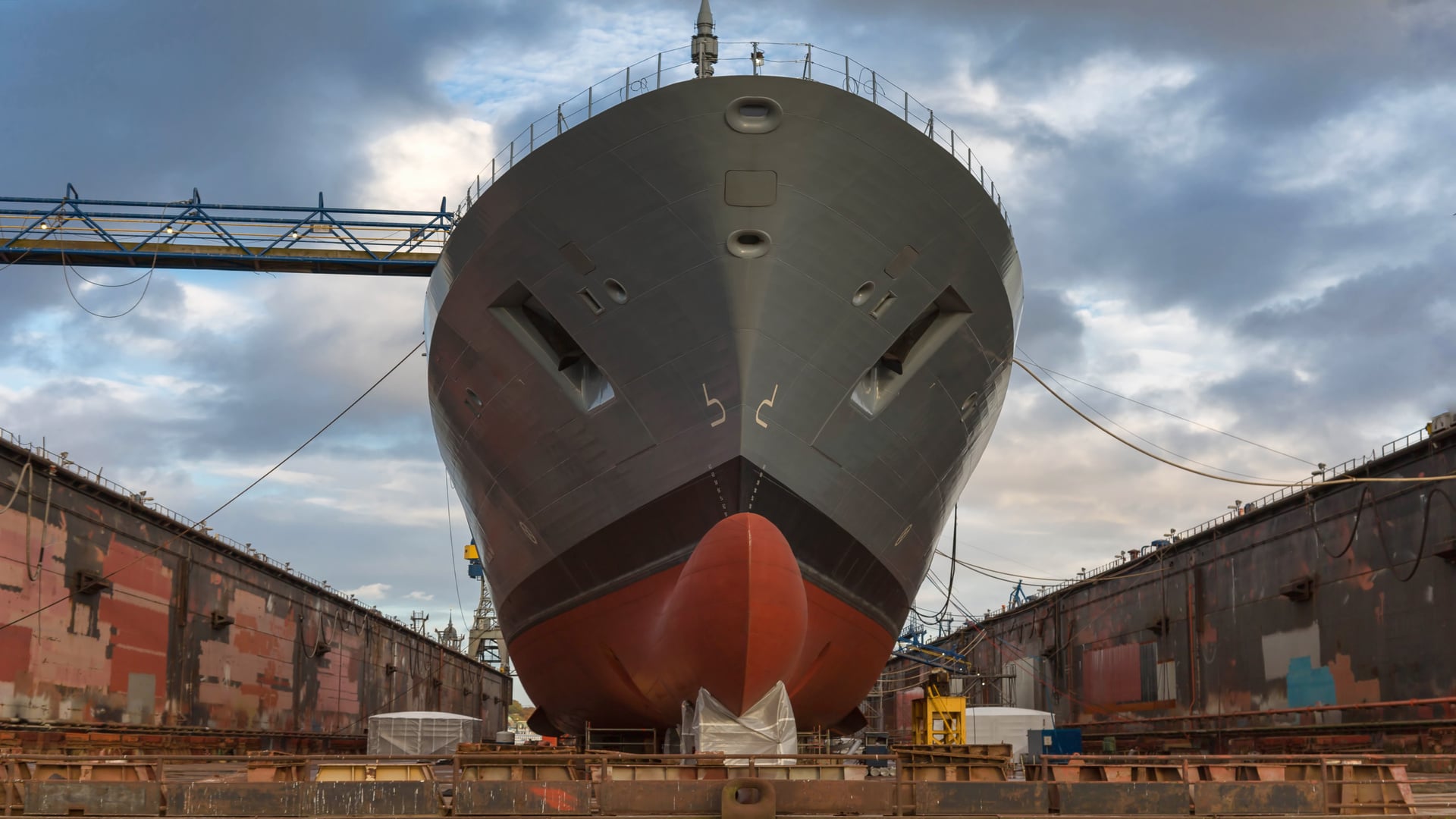 A large warship under construction in a drydock, highlighting the importance of shipyard performance and asset management for efficient shipbuilding.