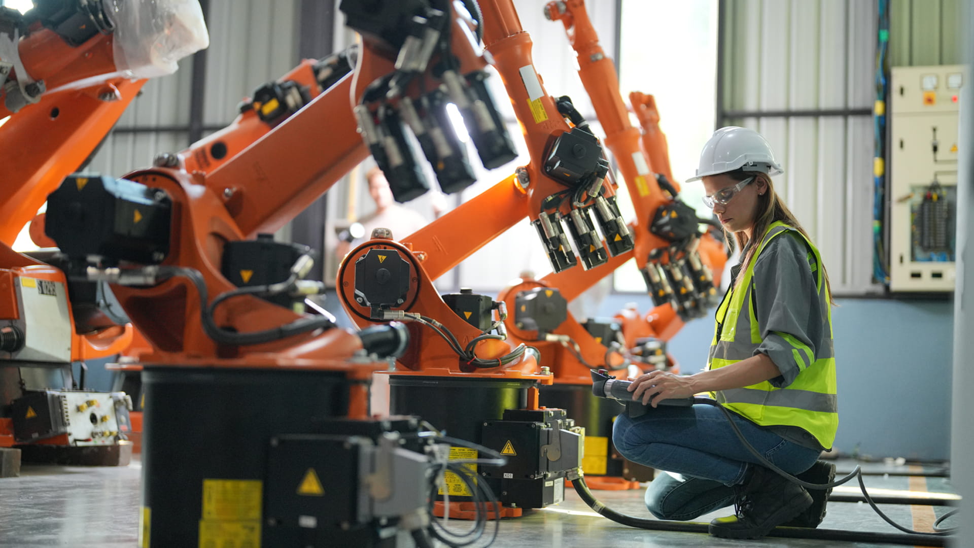 Engineer inspecting robotic arms in an advanced industrial facility.