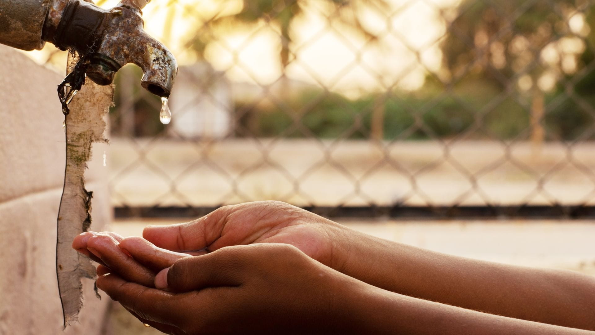 child holding hand under leaking water tap