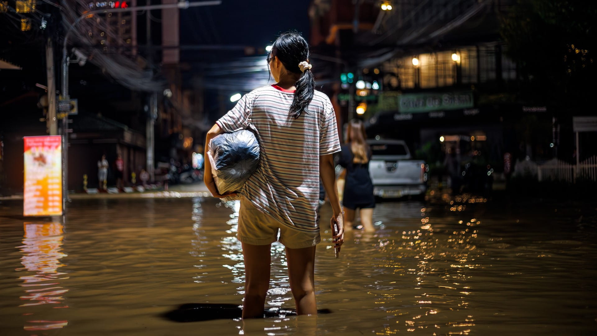 Woman stands in the middle of a flooded street