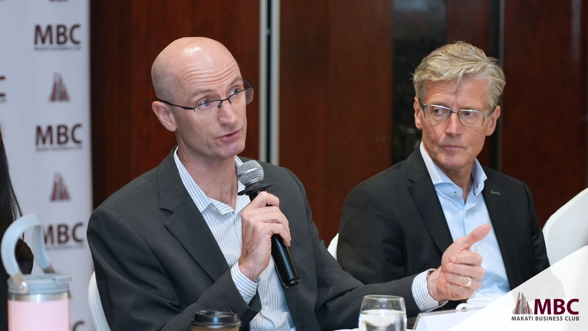 Trevor Morrish-Hale Country Manager of Haskoning Philippines speaks during a Makati Business Club roundtable on offshore wind development, seated beside another panelist. A banner in the background displays the MBC logo.