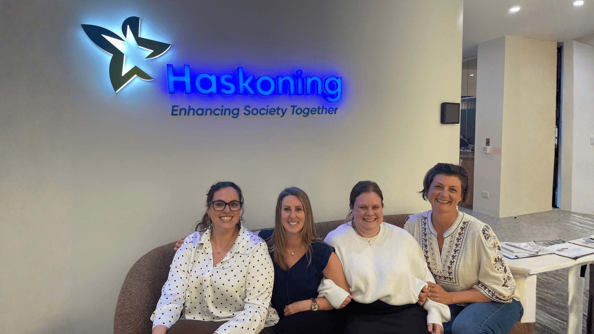 Anna Hahn sitting on couch with 3 colleagues in front of Haskoning sign in the office