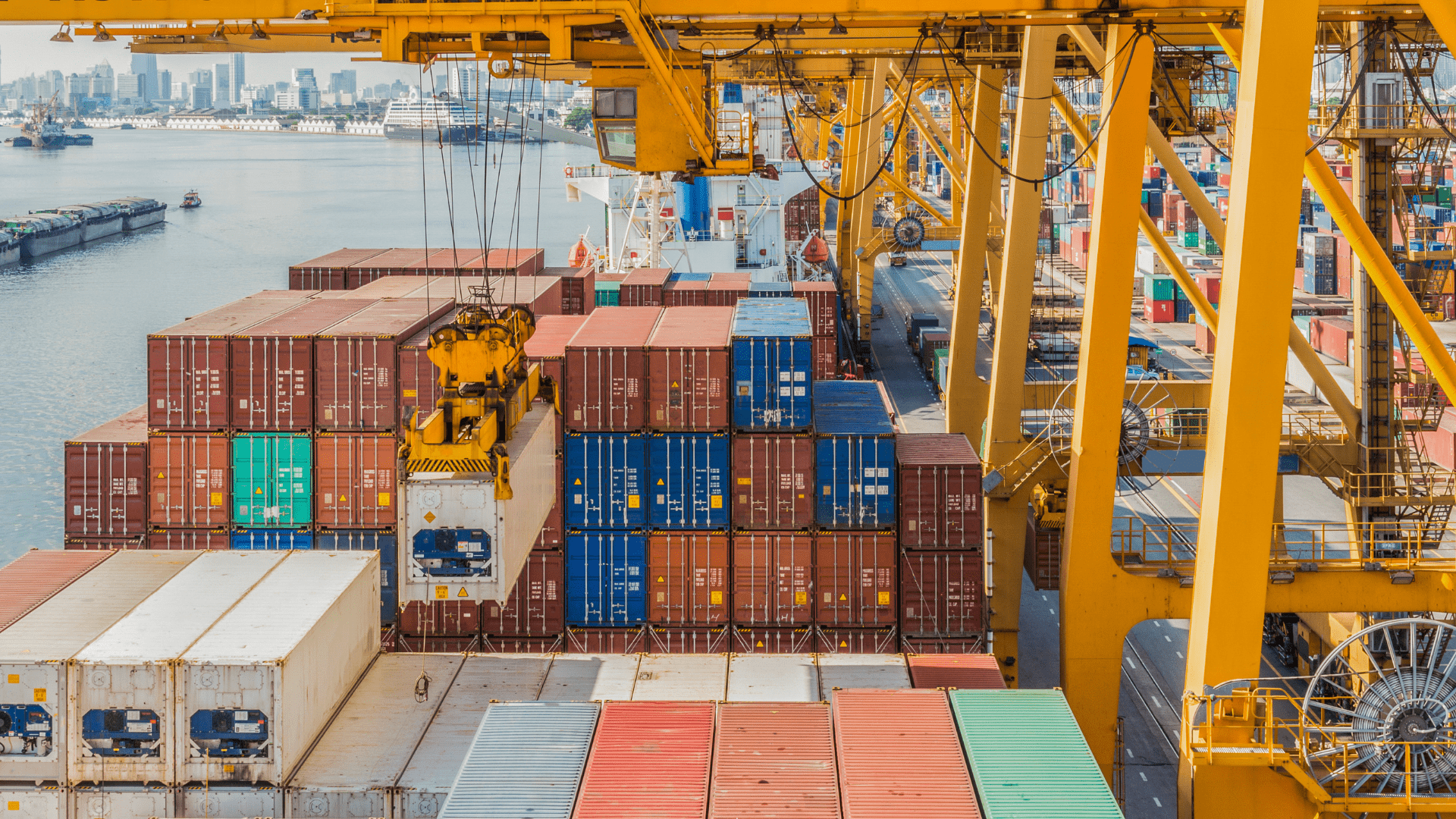 Container terminal with stacked shipping containers and cranes loading cargo vessels, illustrating global supply chains under pressure and resilient network design.