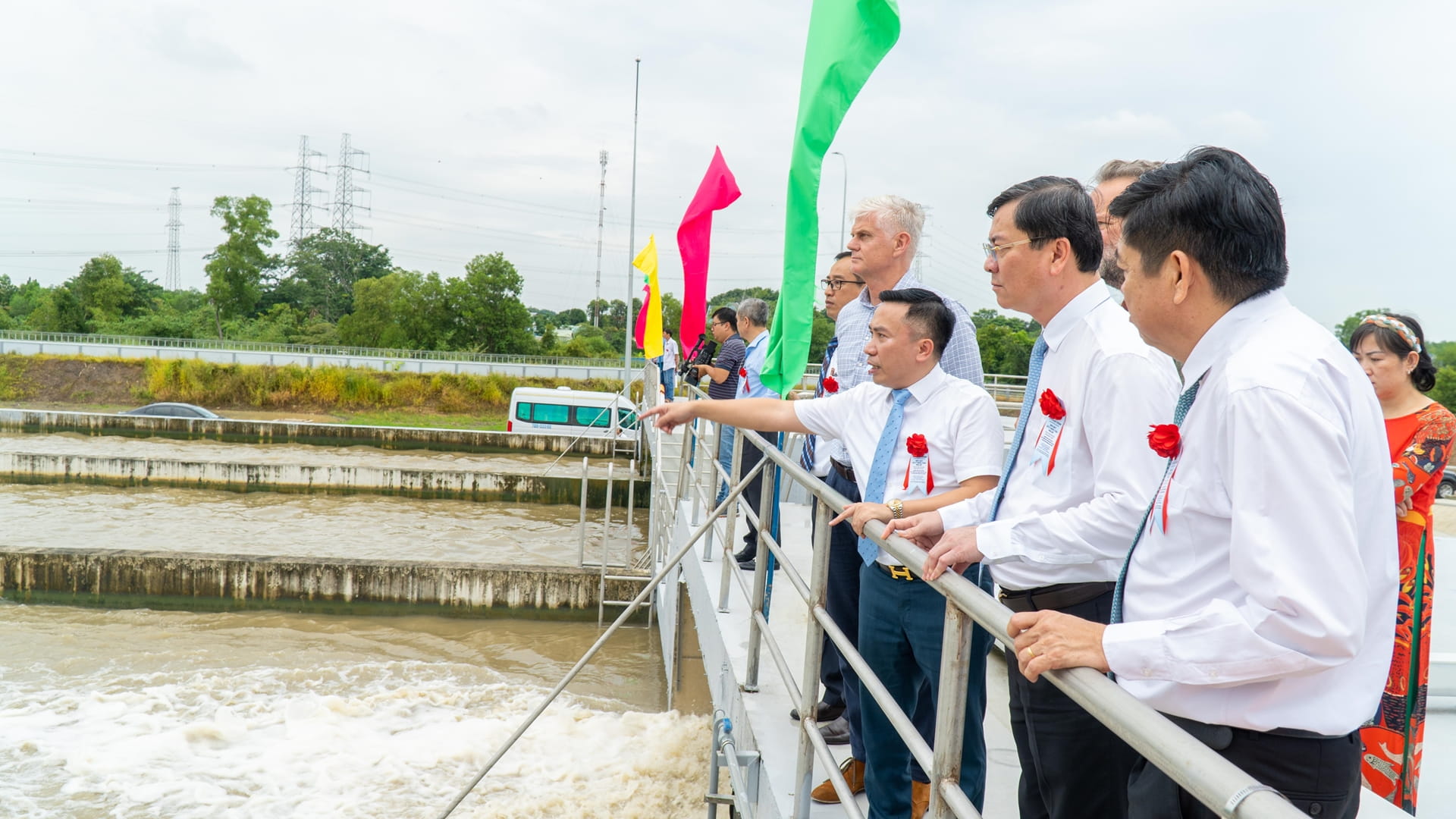 Several people dressed in white shirts and ties observe the river from a bridge.