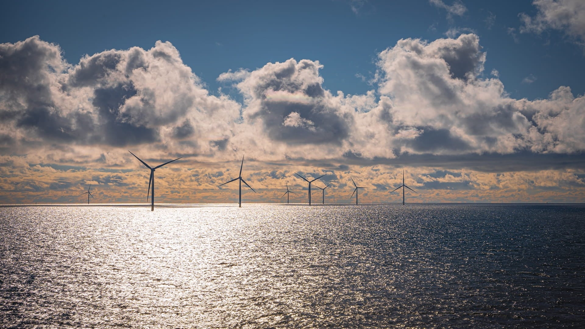 Offshore wind turbines at sea under a cloudy sky