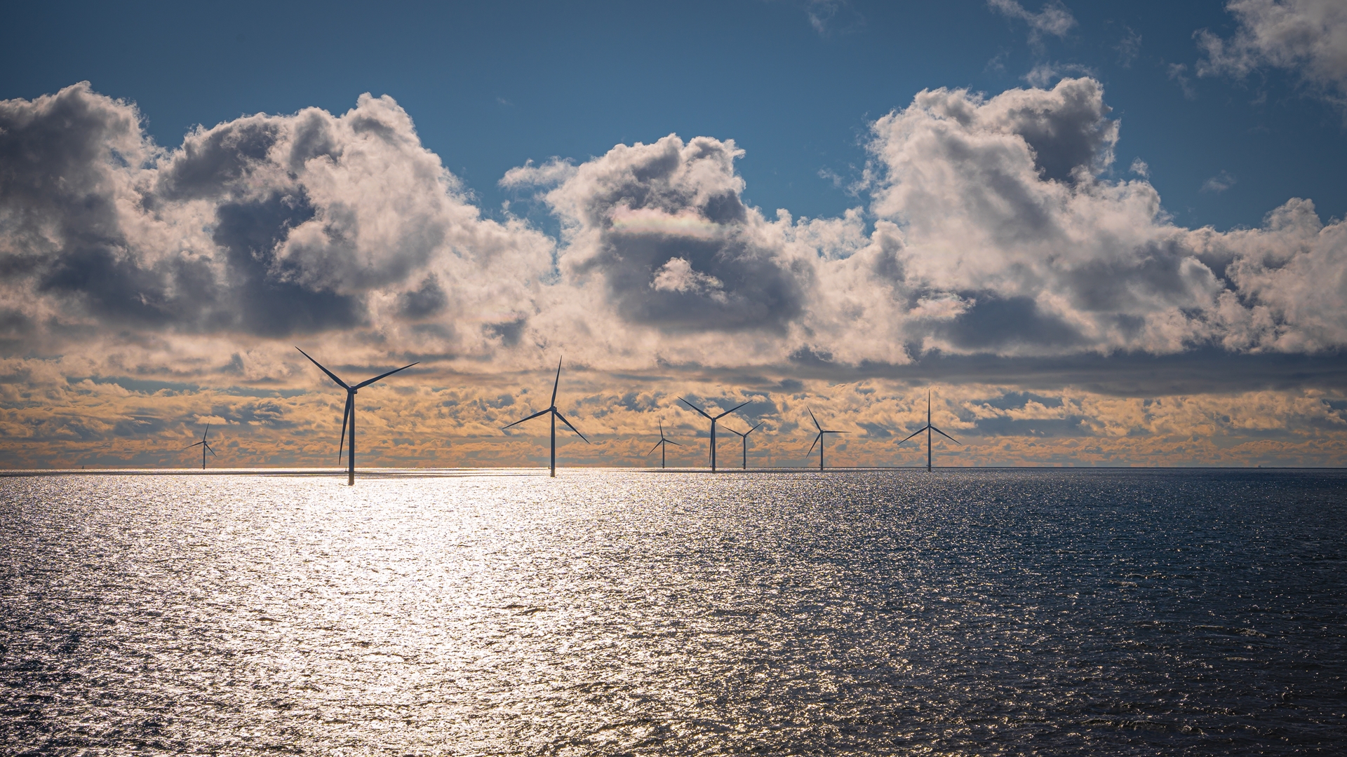 Offshore wind turbines at sea under a cloudy sky