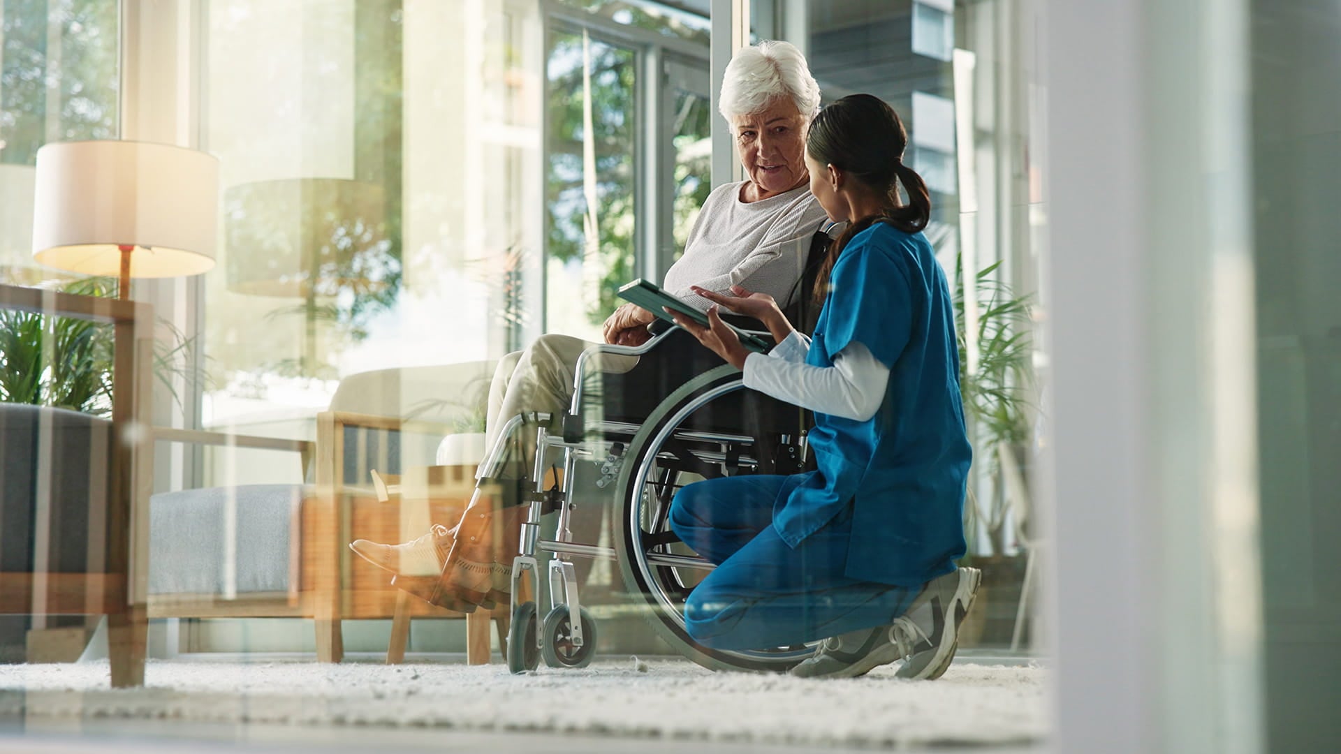 Elderly person in a wheelchair with a nurse