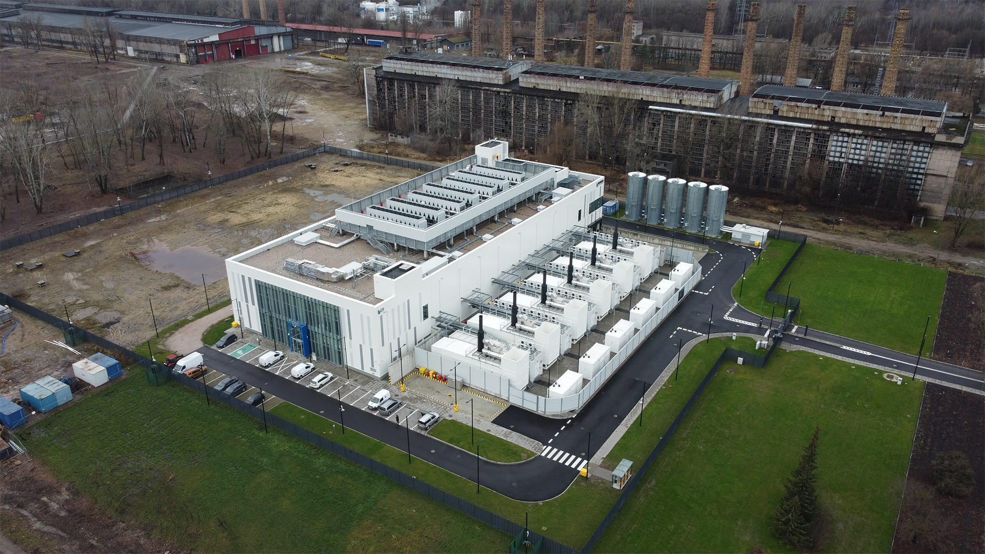 Aerial view of the new Warsaw data centre, showcasing its modern design with a large white building featuring multiple cooling units.