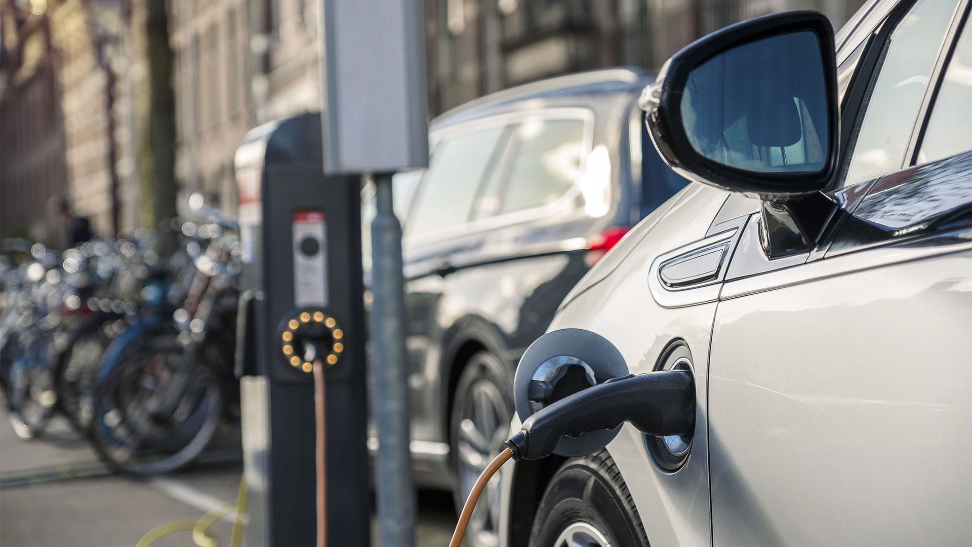 Electric car being charged at charging post in the city