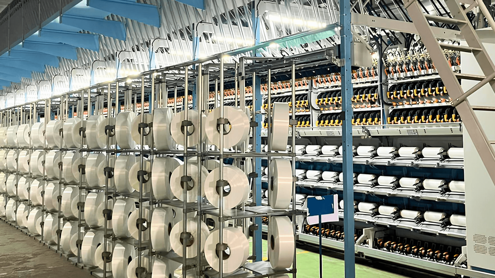 Industrial textile manufacturing facility with yarn spools and automated spinning machines in operation
