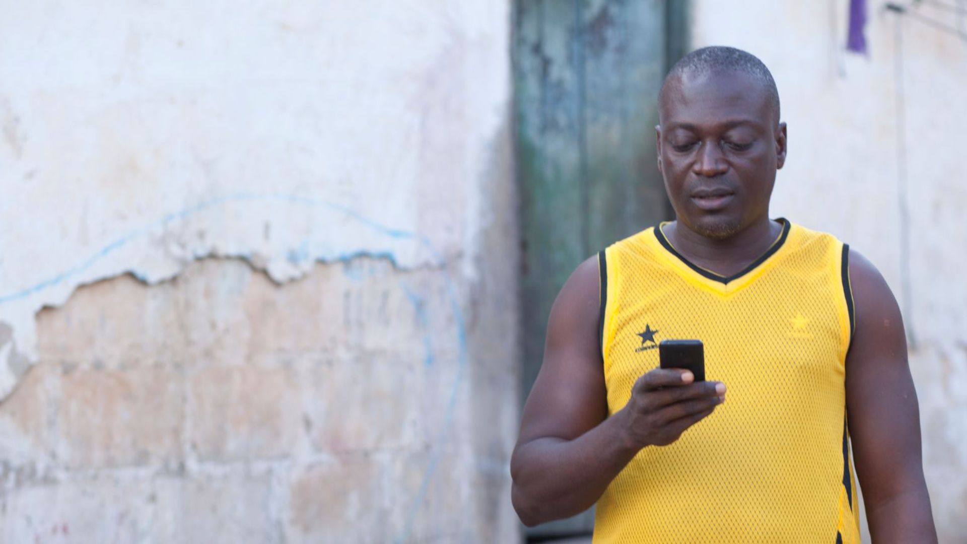 man standing in front of wall looking at his phone