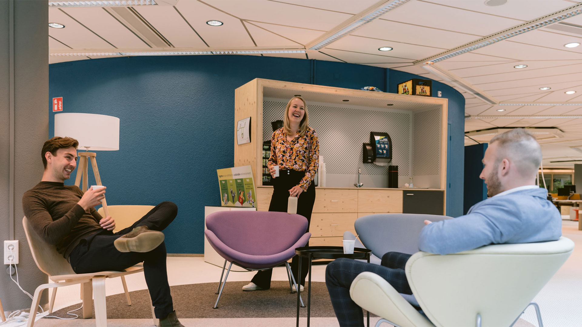 Three colleagues at work chatting in the lounge area