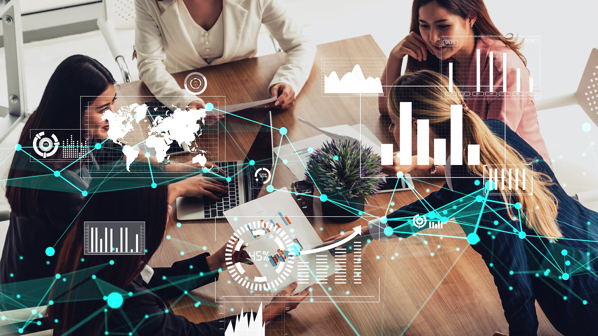 Women at a desk in the office checking their laptops and smart phones