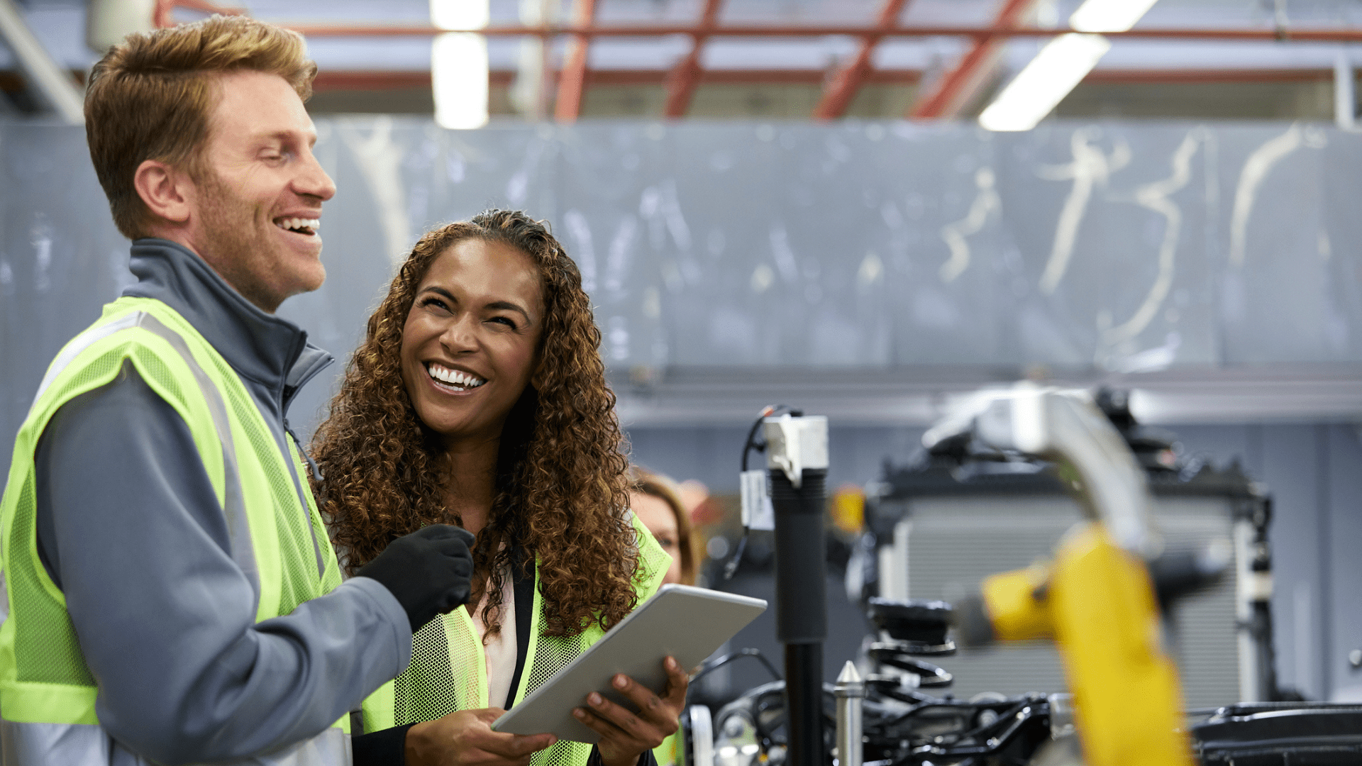 Engineers using digital tablet in manufacturing facility to optimise asset performance and drive operational excellence in asset-intensive industry