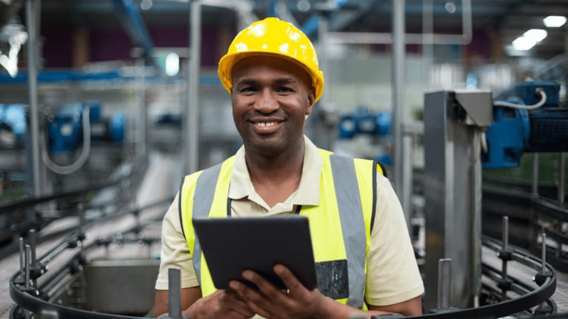 Industrial operator using digital tablet in manufacturing facility, supporting operational excellence and data-driven high-performance operations