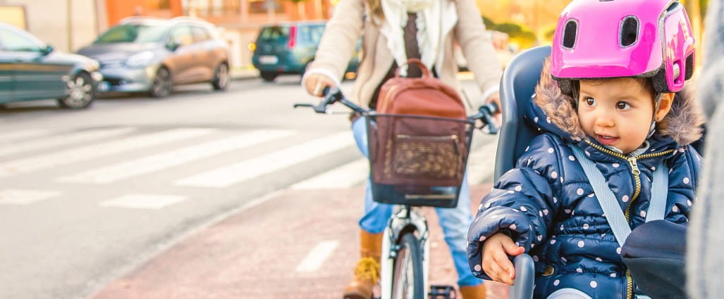 two people cycling on their bikes with a baby in the back seat of one of the bikes