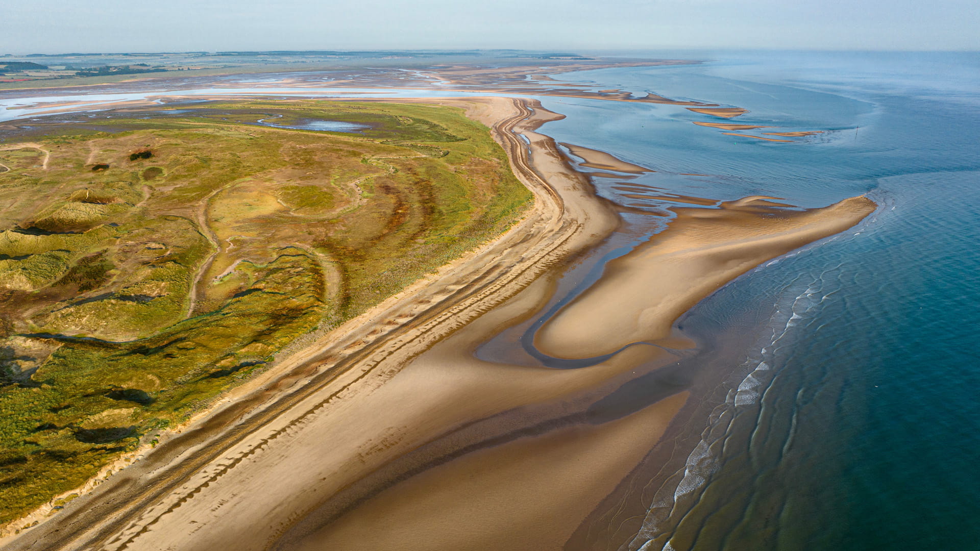 aerial view of sand dunes next to sandy beach