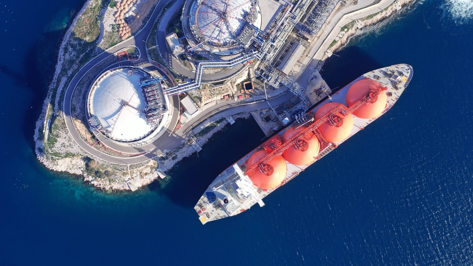  LNG (Liquified Natural Gas) tanker anchored in small gas terminal island with tanks for storage