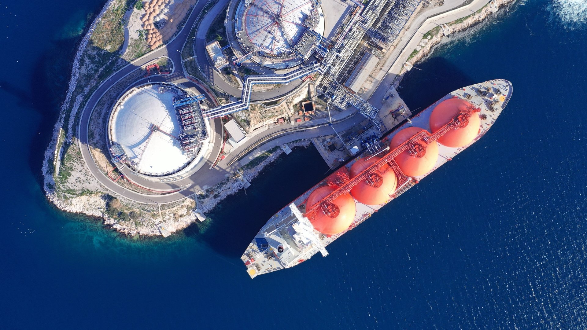 LNG (Liquified Natural Gas) tanker anchored in small gas terminal island with tanks for storage