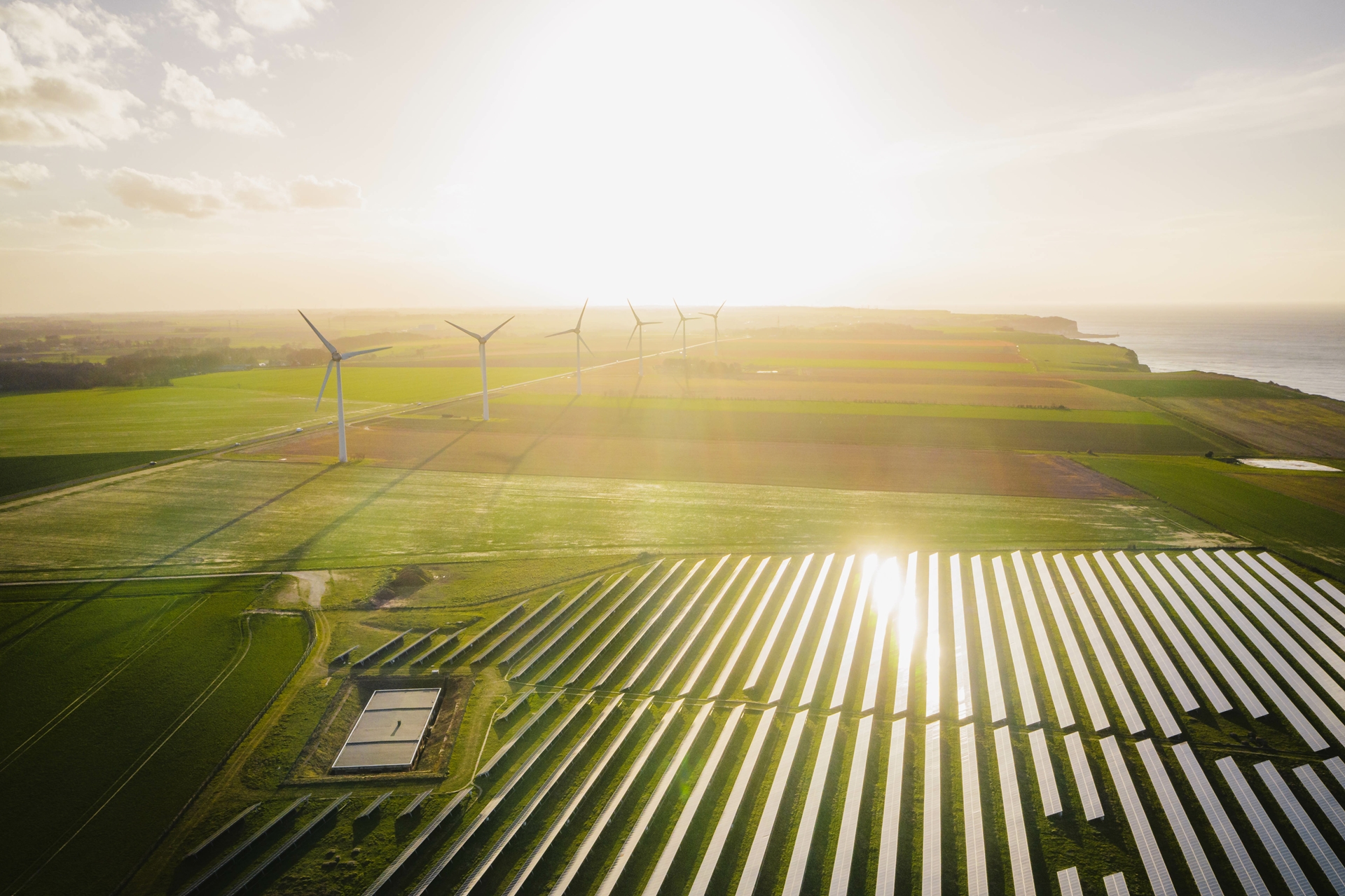 Farm landscape with wind turbines and solar panels.